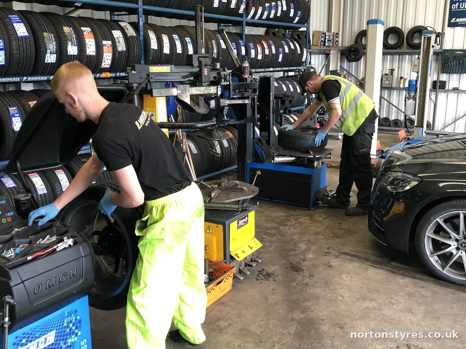 Fitters balancing car wheels in the Nortons Tyres car bay, close view Fitters balancing car wheels in the Nortons Tyres car bay, close view