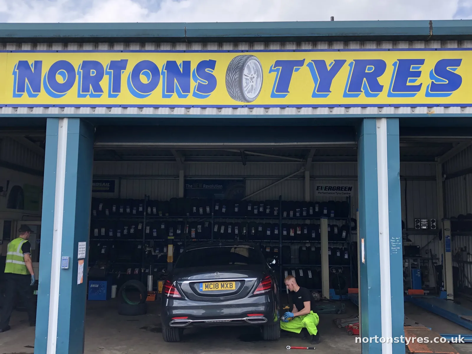 Nortons Tyres car bay with a car being worked on inside, close view Nortons Tyres car bay with a car being worked on inside, close view