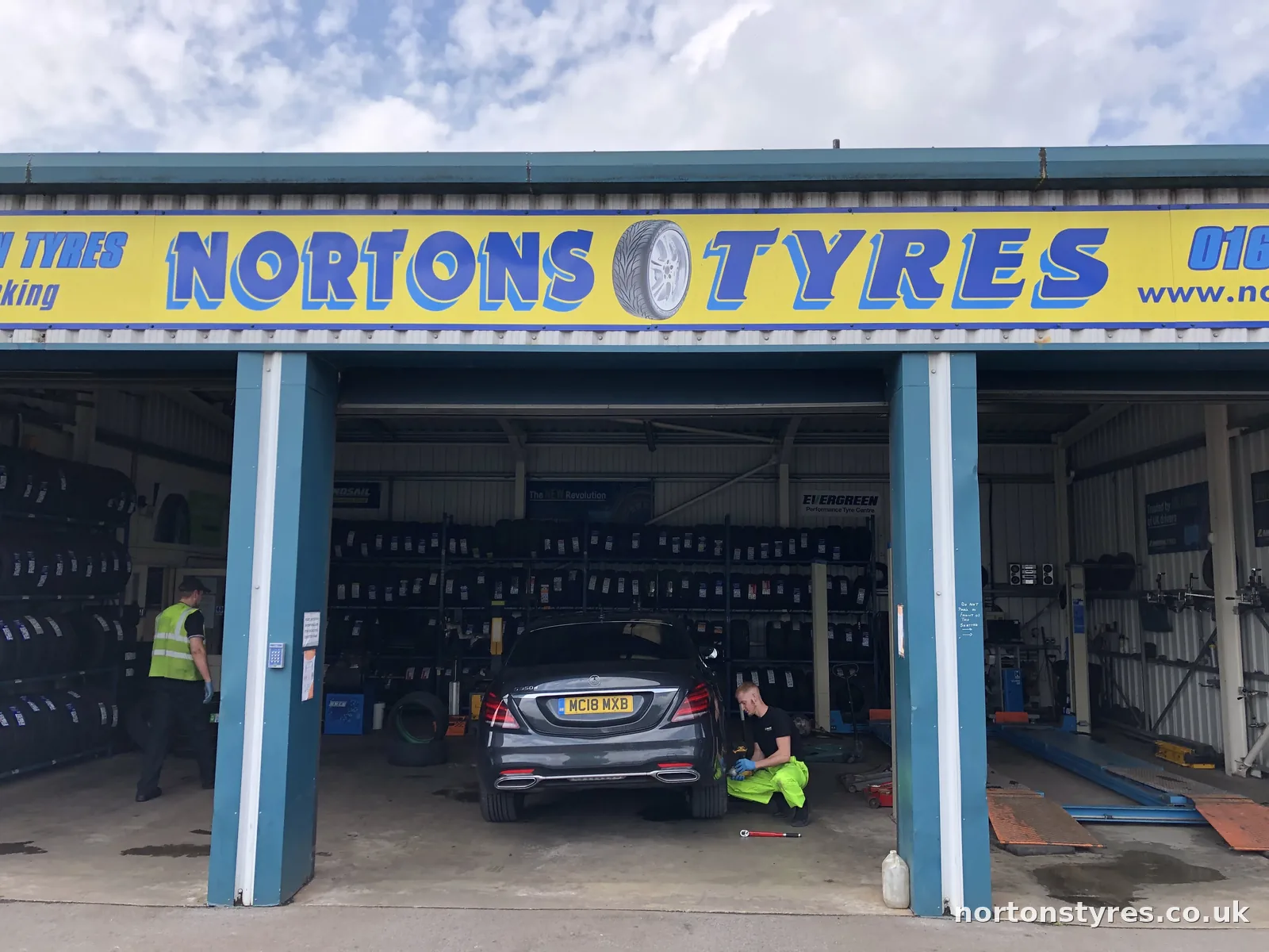 Nortons Tyres car bay with a car being worked on inside Nortons Tyres car bay with a car being worked on inside