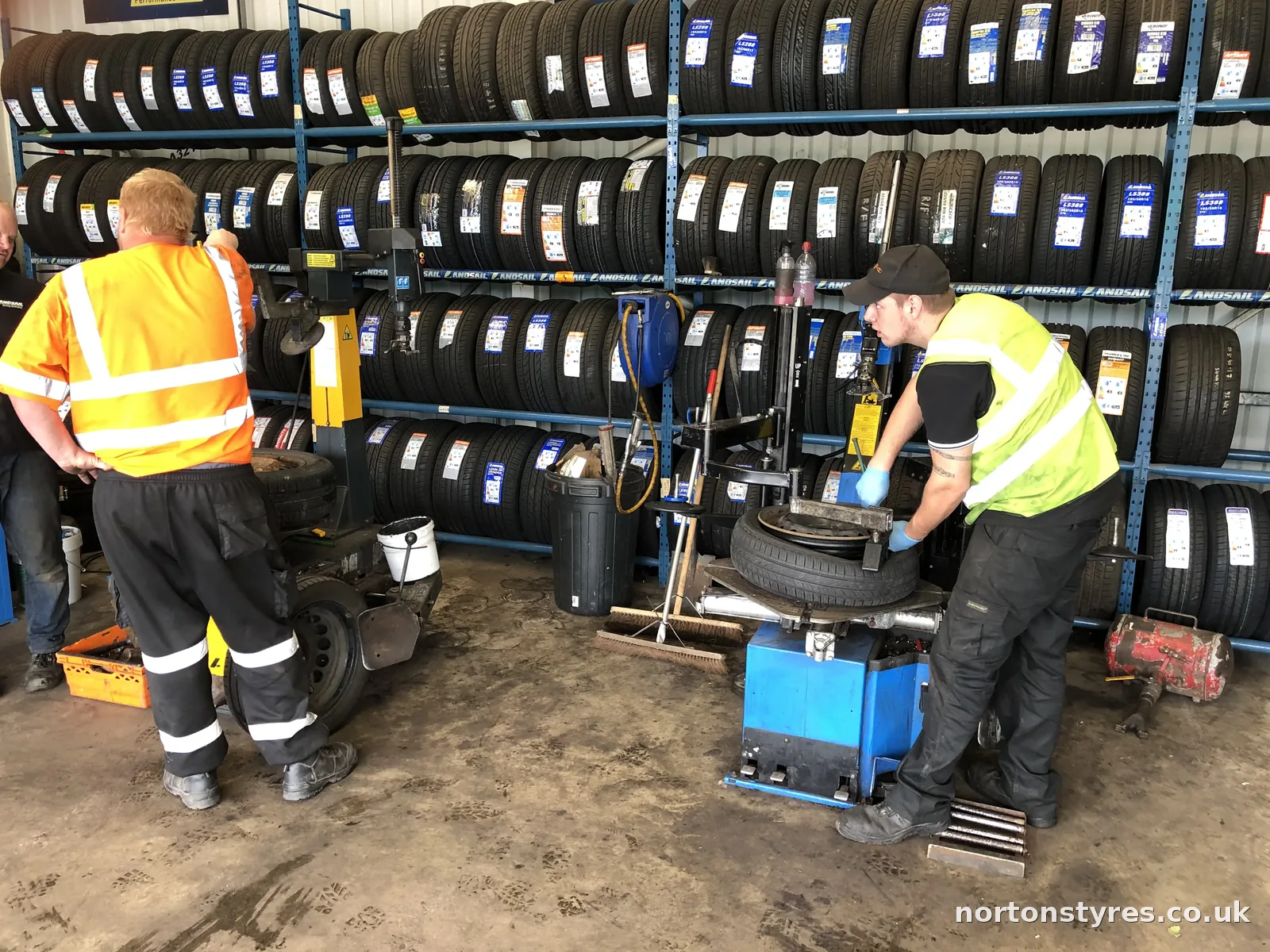 Two fitters changing a car tyre on the machine in the tyre bay Two fitters changing a car tyre on the machine in the tyre bay