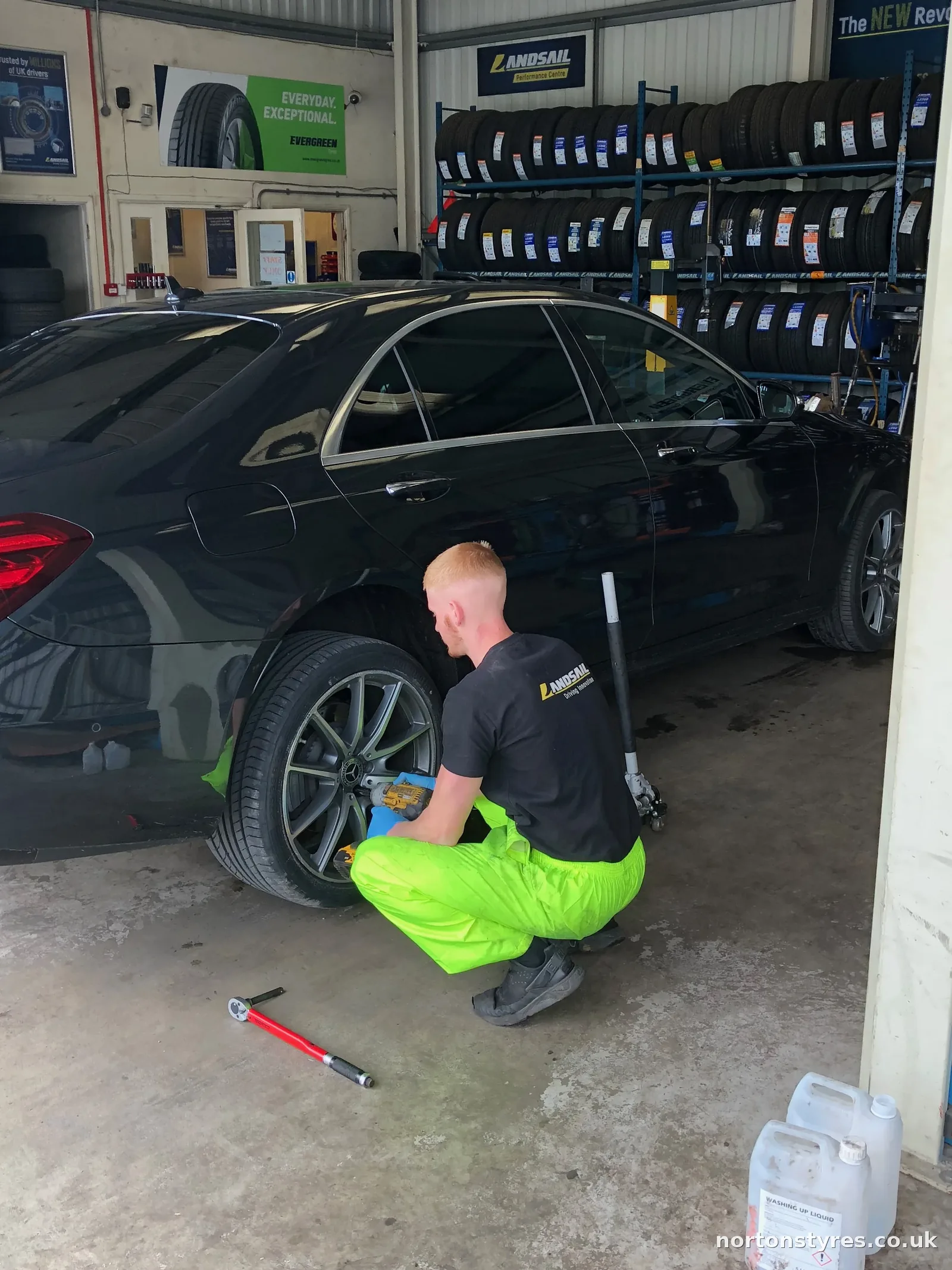 Fitter changing the wheel on a saloon car in the tyre bay, close view Fitter changing the wheel on a saloon car in the tyre bay, close view