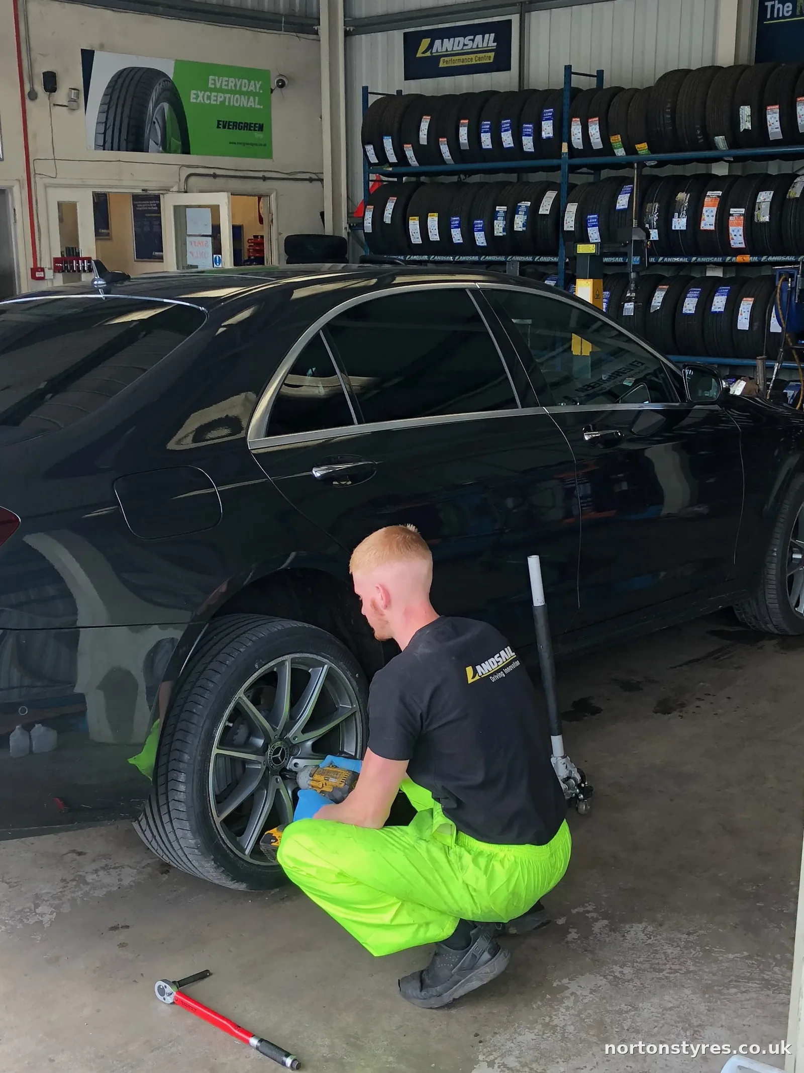 Fitter changing the wheel on a saloon car in the tyre bay, detail Fitter changing the wheel on a saloon car in the tyre bay, detail