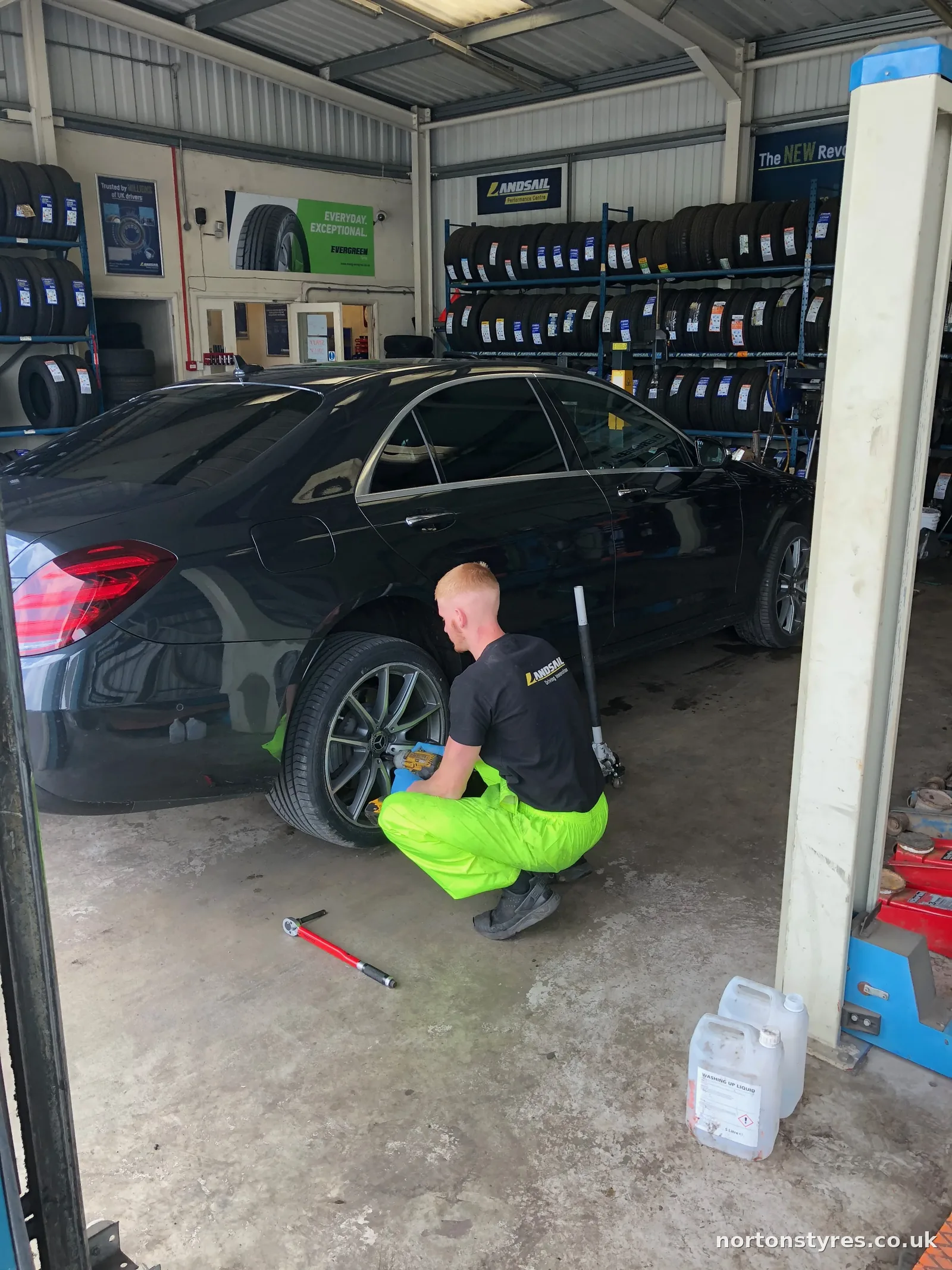 Fitter changing the wheel on a saloon car in the tyre bay Fitter changing the wheel on a saloon car in the tyre bay