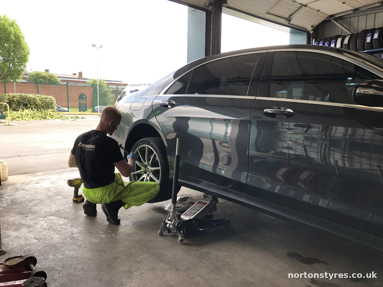 Fitter refitting the wheel on a car outside the tyre bay Fitter refitting the wheel on a car outside the tyre bay