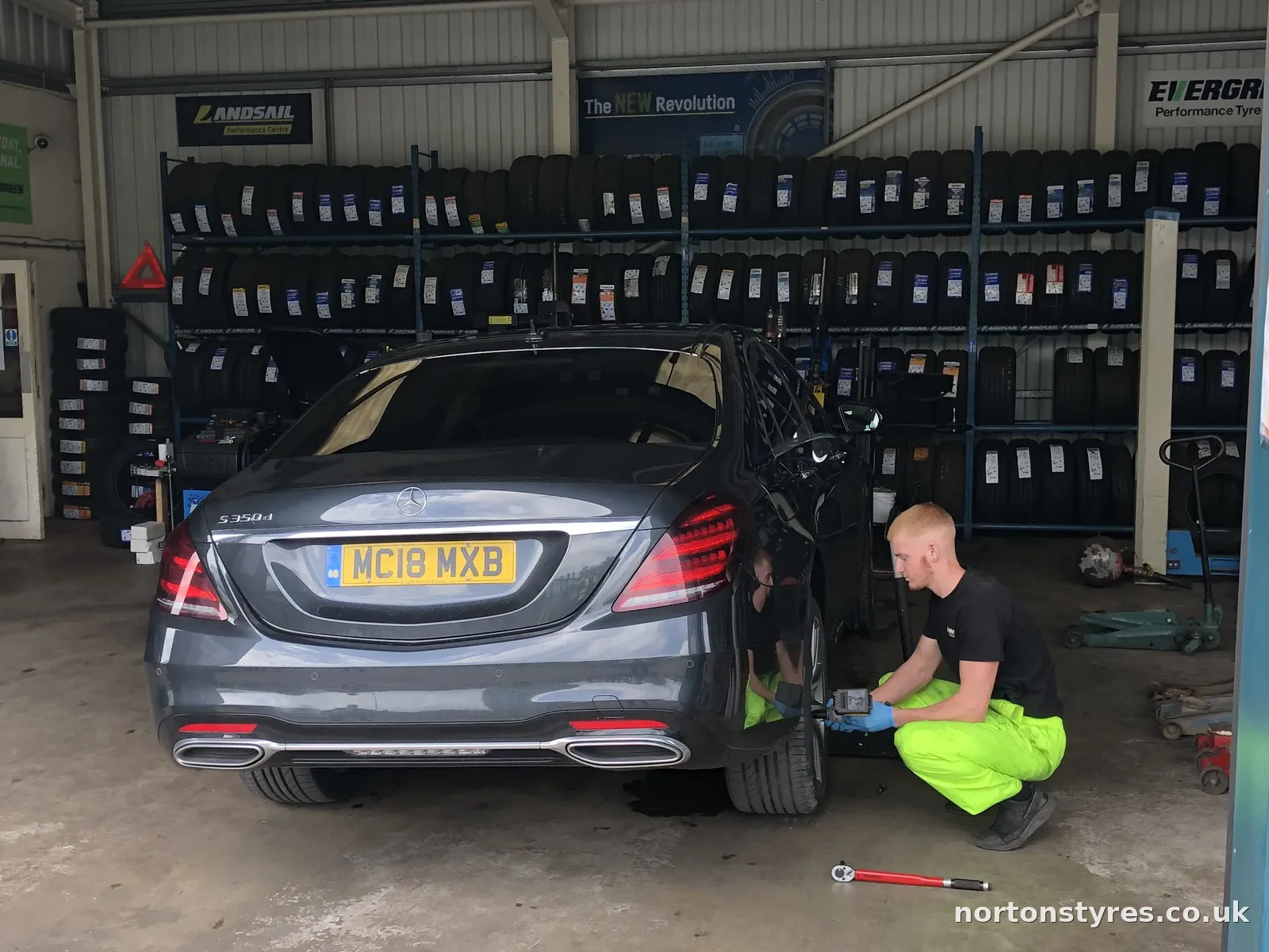 Saloon car in the bay with the fitter at the rear wheel, detail Saloon car in the bay with the fitter at the rear wheel, detail