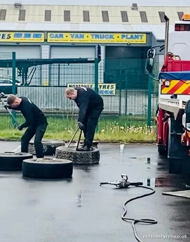 Fitters working on truck tyres in the yard beside a recovery truck, close view Fitters working on truck tyres in the yard beside a recovery truck, close view