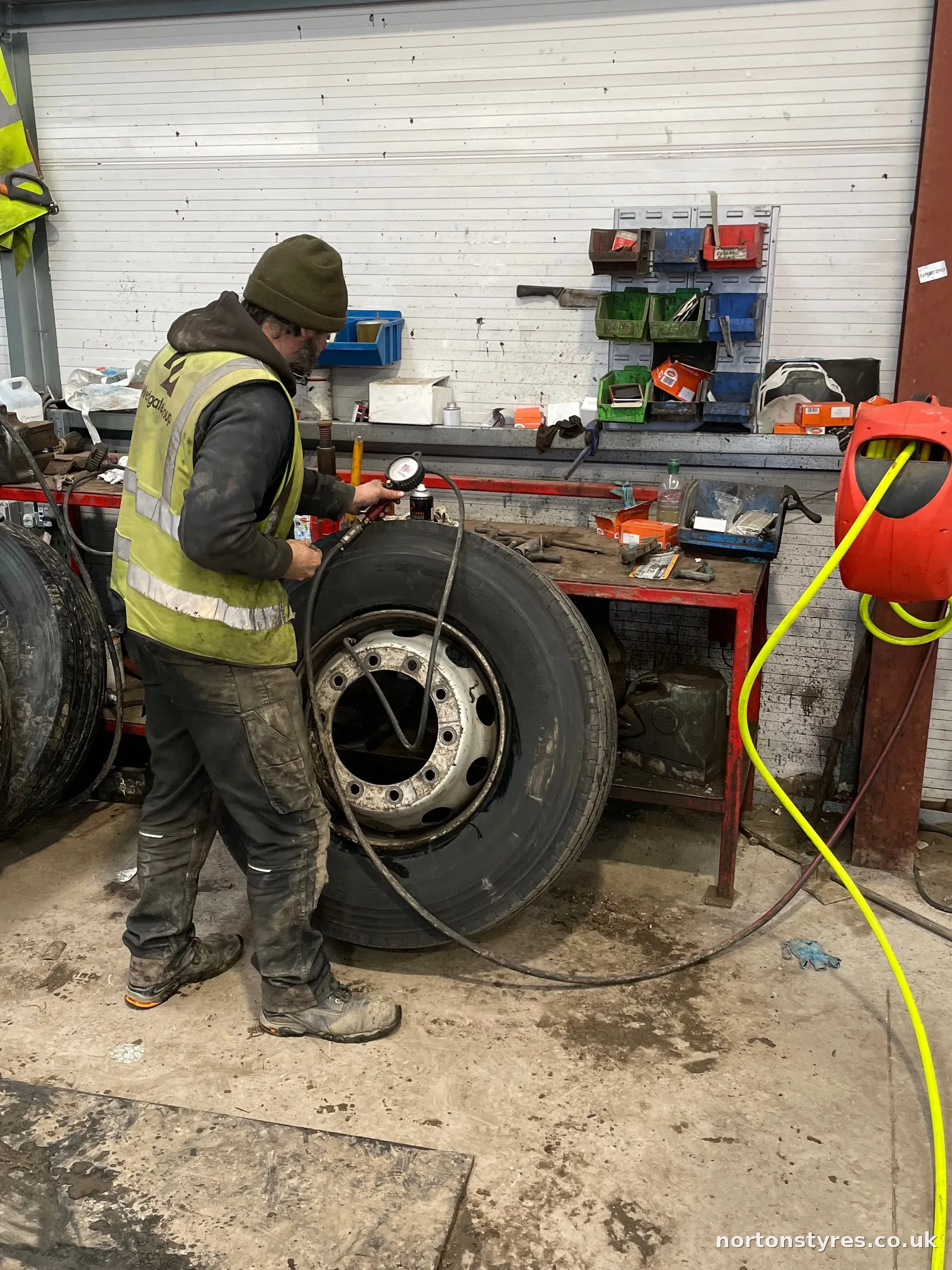 Fitter with truck wheels in the commercial tyre workshop, close view Fitter with truck wheels in the commercial tyre workshop, close view