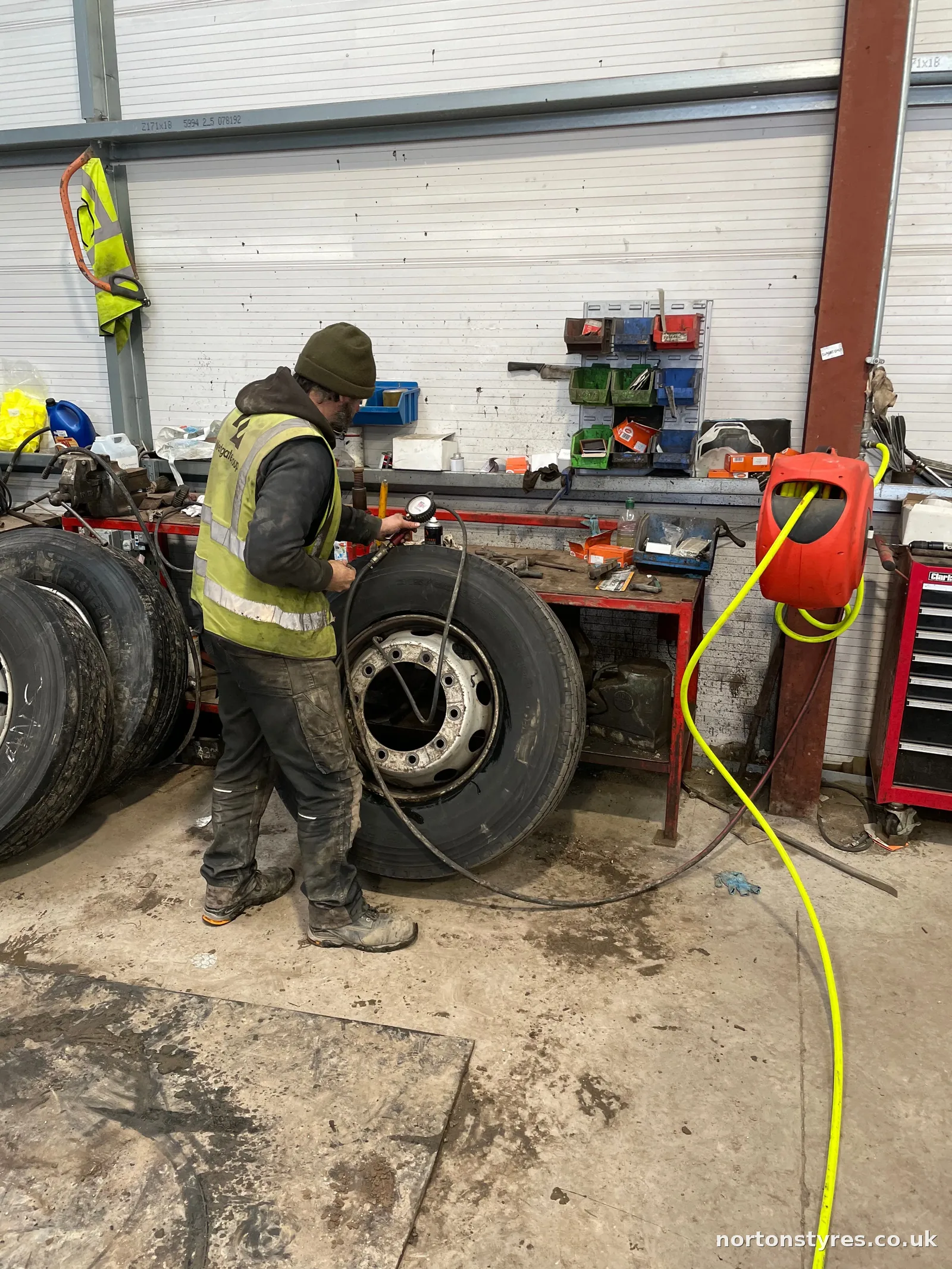 Fitter with truck wheels in the commercial tyre workshop Fitter with truck wheels in the commercial tyre workshop