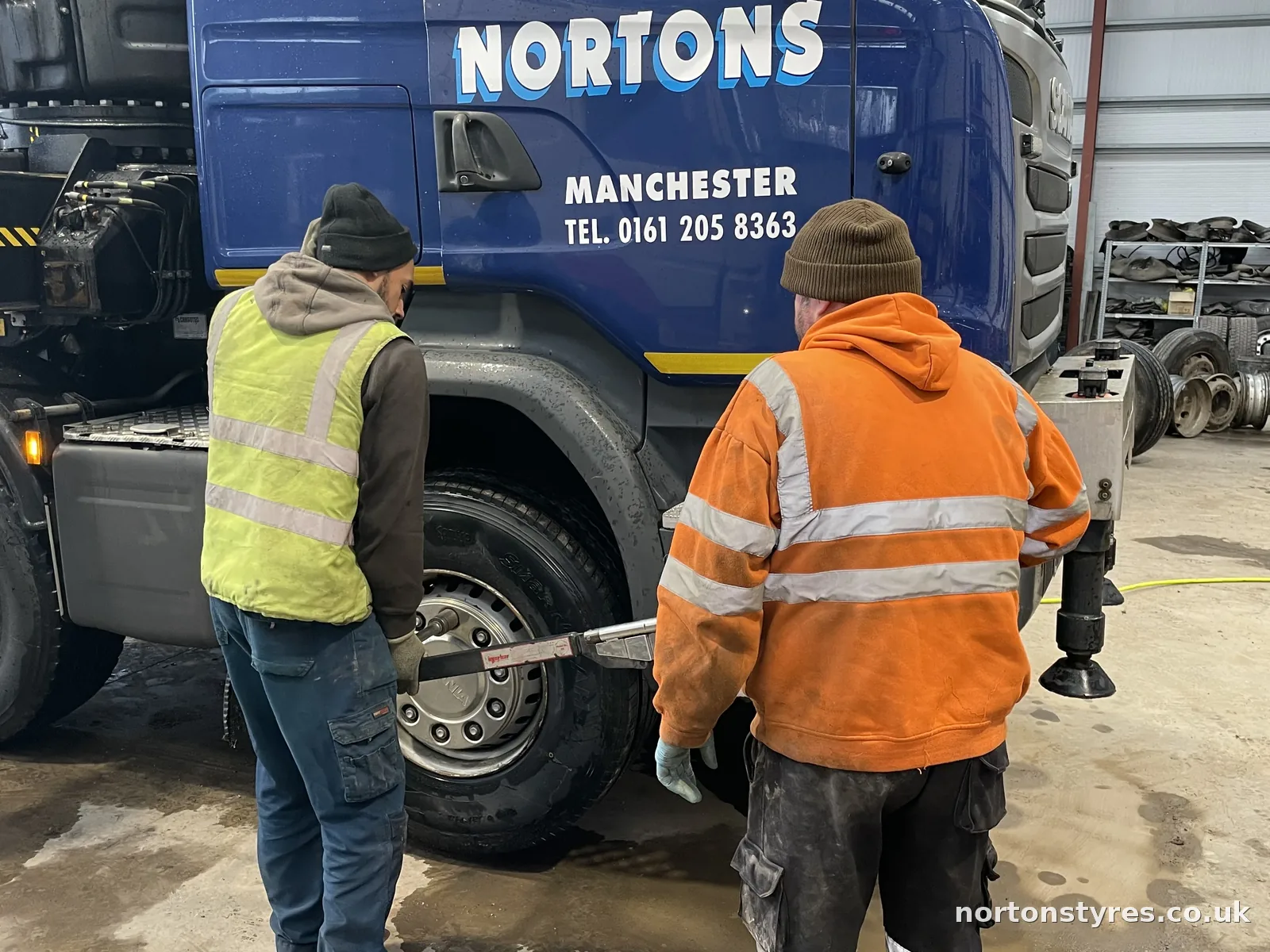 Fitters changing a wheel on a Nortons lorry in the commercial bay, close view Fitters changing a wheel on a Nortons lorry in the commercial bay, close view