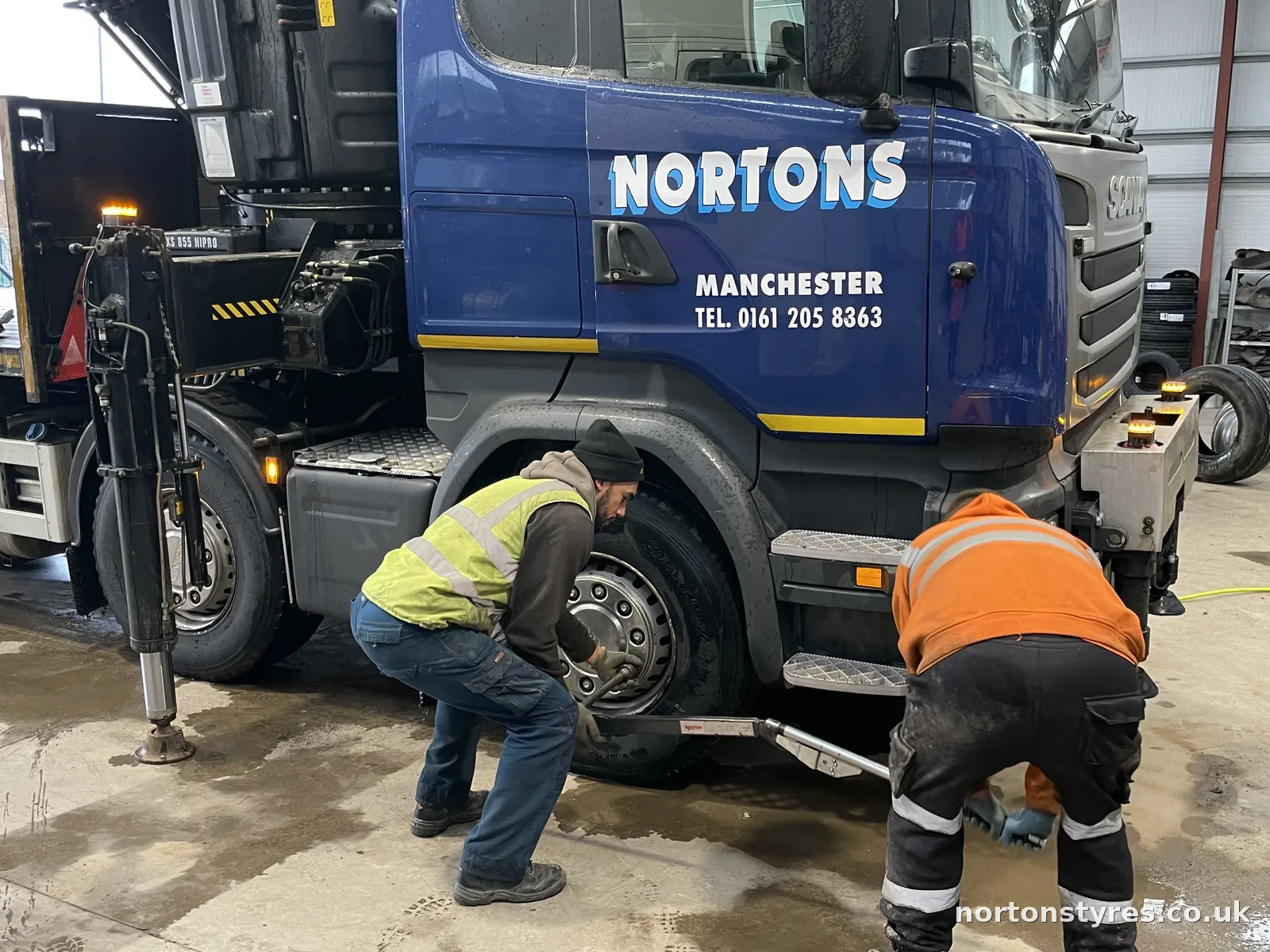 Fitters working on the front wheel of a Nortons lorry, close view Fitters working on the front wheel of a Nortons lorry, close view