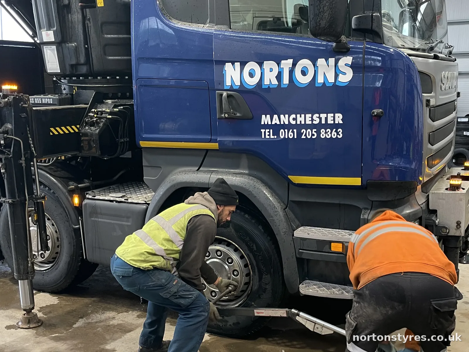 Fitters working on the front wheel of a Nortons lorry, detail Fitters working on the front wheel of a Nortons lorry, detail