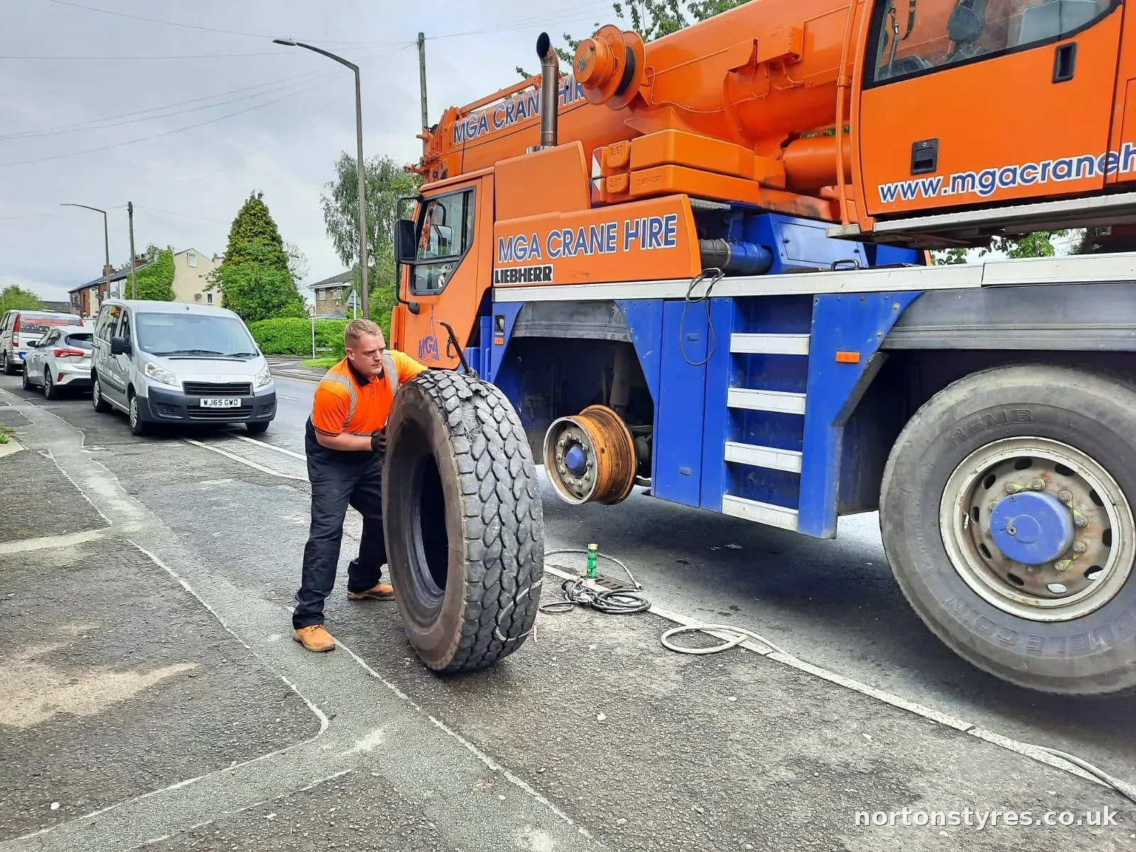 Fitter rolling a new tyre to a mobile crane at the roadside Fitter rolling a new tyre to a mobile crane at the roadside