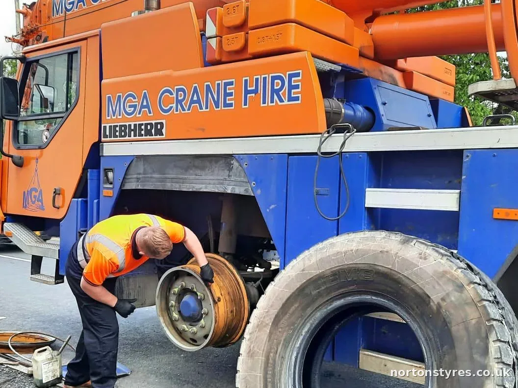 Fitter changing a mobile crane tyre at the kerbside, detail Fitter changing a mobile crane tyre at the kerbside, detail
