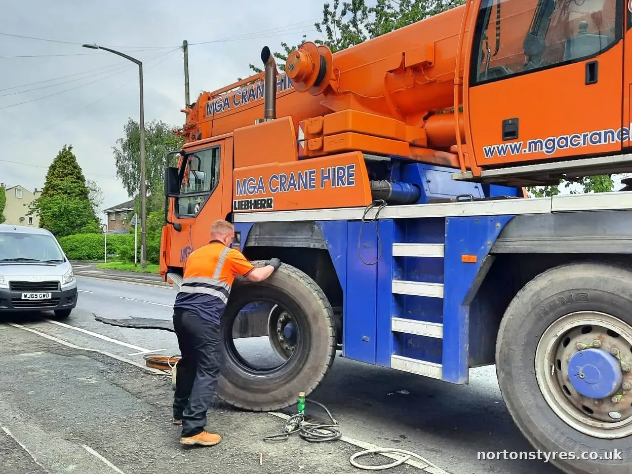 Fitter lifting a crane tyre into place, close view Fitter lifting a crane tyre into place, close view