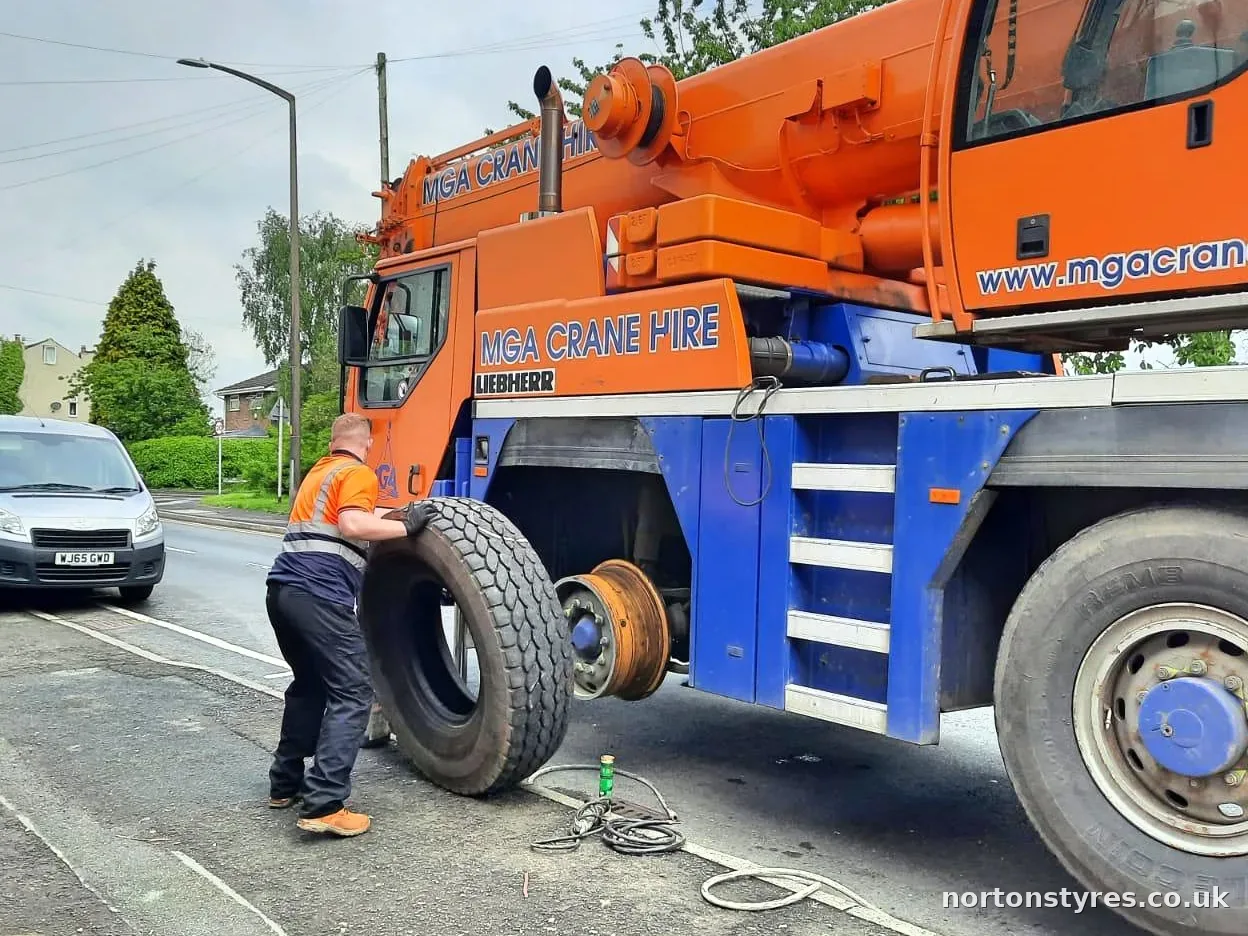 Fitter handling a crane tyre next to the wheel hub, close view Fitter handling a crane tyre next to the wheel hub, close view