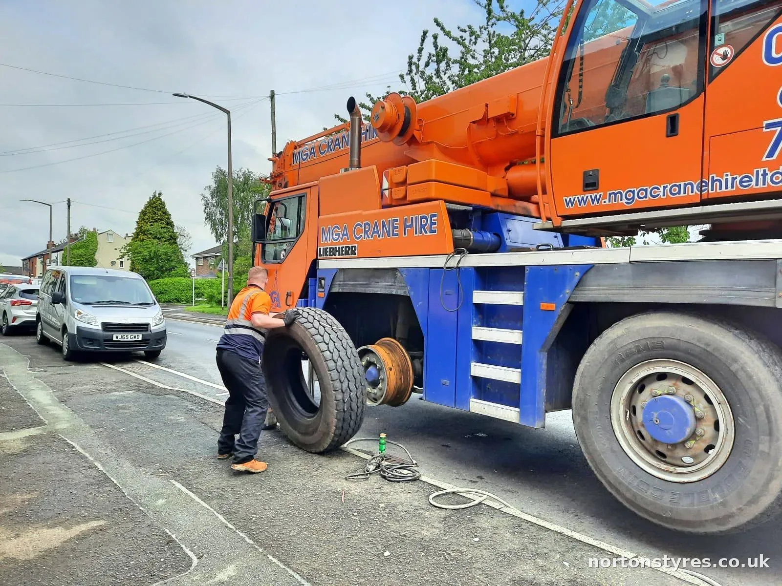 Fitter handling a crane tyre next to the wheel hub Fitter handling a crane tyre next to the wheel hub