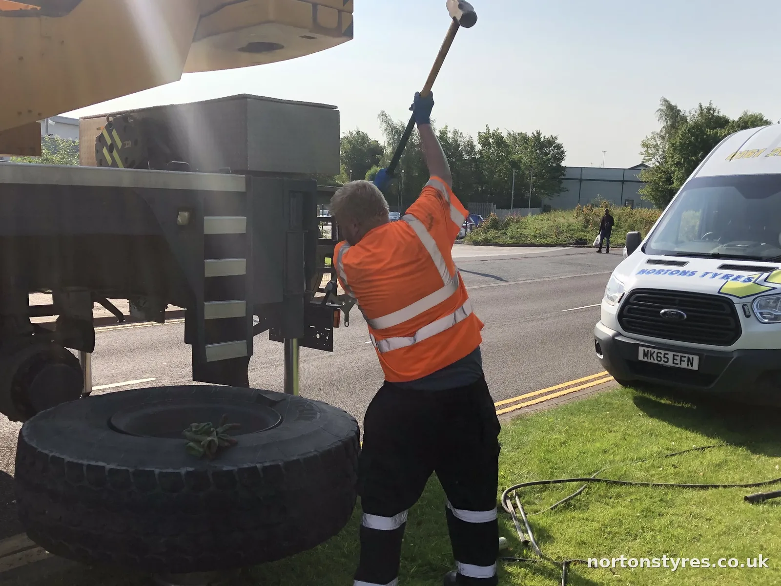 Fitter breaking the bead on a large plant tyre beside the Nortons van, close view Fitter breaking the bead on a large plant tyre beside the Nortons van, close view