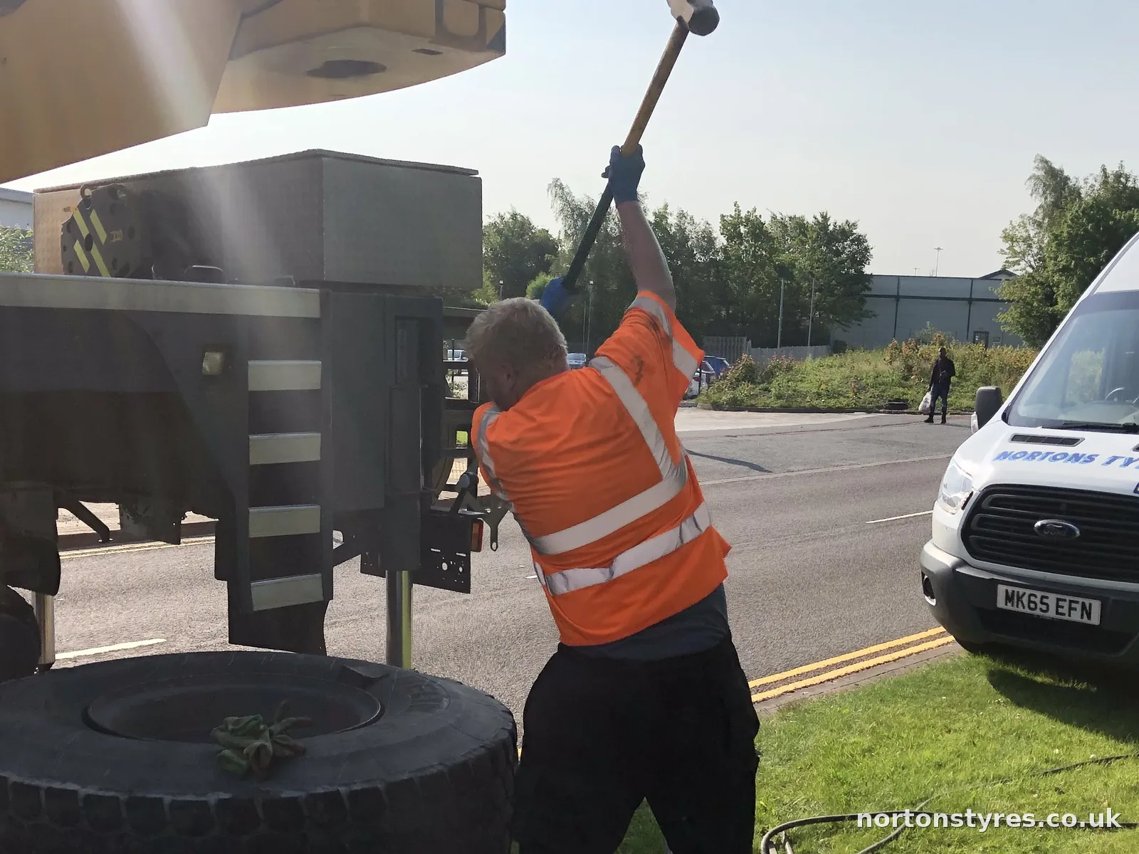 Fitter breaking the bead on a large plant tyre beside the Nortons van, detail Fitter breaking the bead on a large plant tyre beside the Nortons van, detail