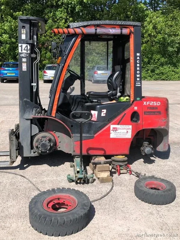 Forklift with a wheel off and its tyres being changed, close view Forklift with a wheel off and its tyres being changed, close view
