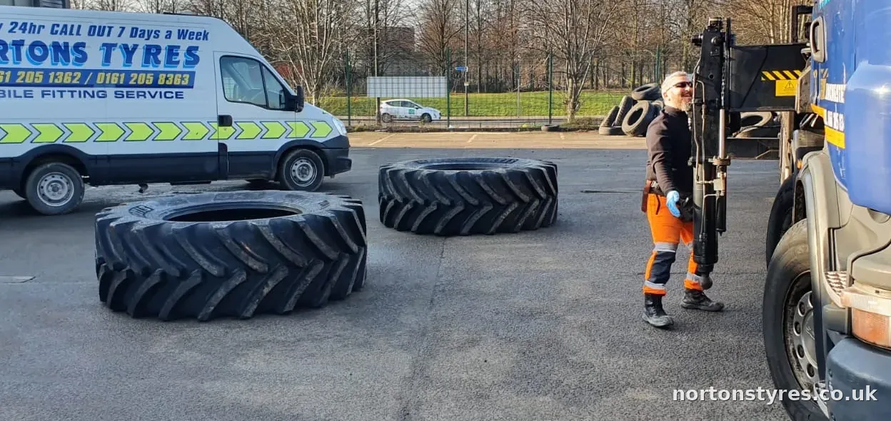 Fitter with large tractor tyres beside the Nortons Tyres van, close view Fitter with large tractor tyres beside the Nortons Tyres van, close view