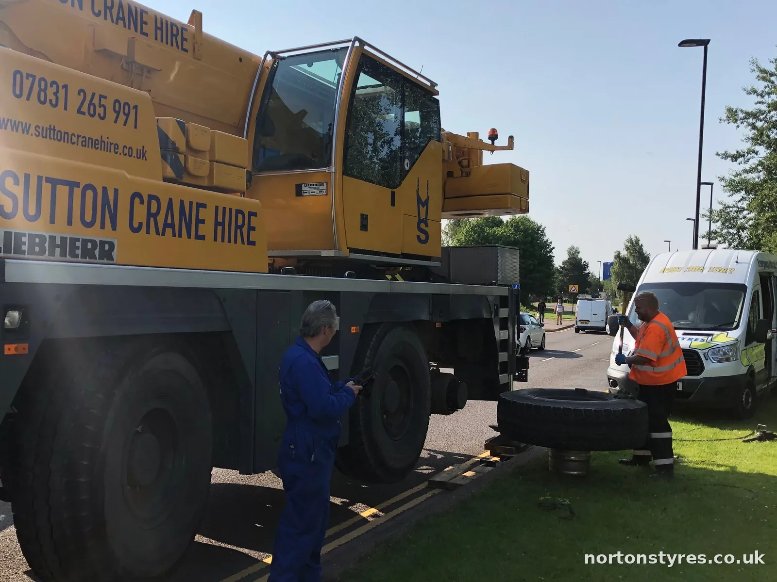 Fitters changing a tyre on a mobile crane with the Nortons van behind, close view Fitters changing a tyre on a mobile crane with the Nortons van behind, close view