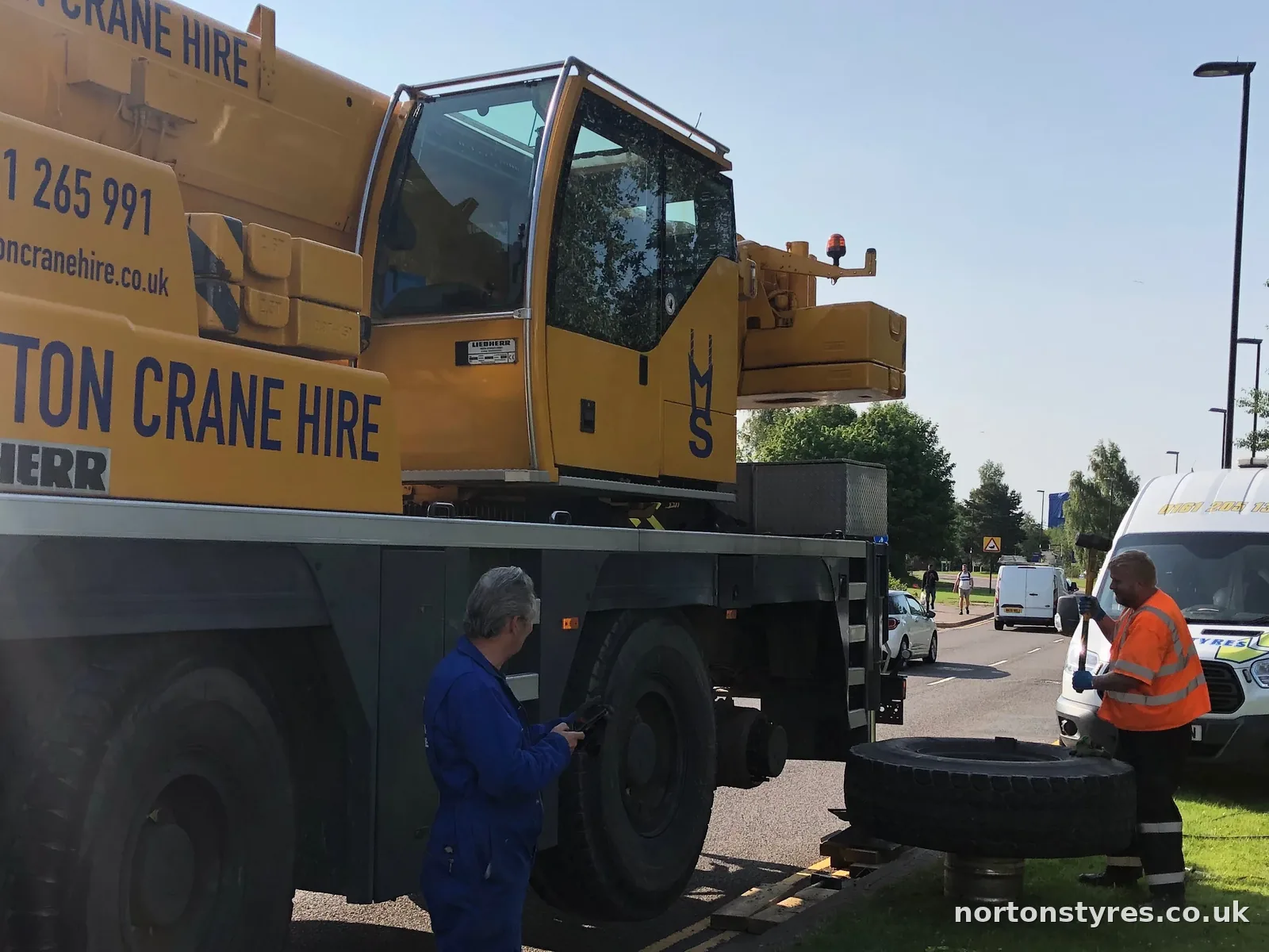 Fitters changing a tyre on a mobile crane with the Nortons van behind, detail Fitters changing a tyre on a mobile crane with the Nortons van behind, detail