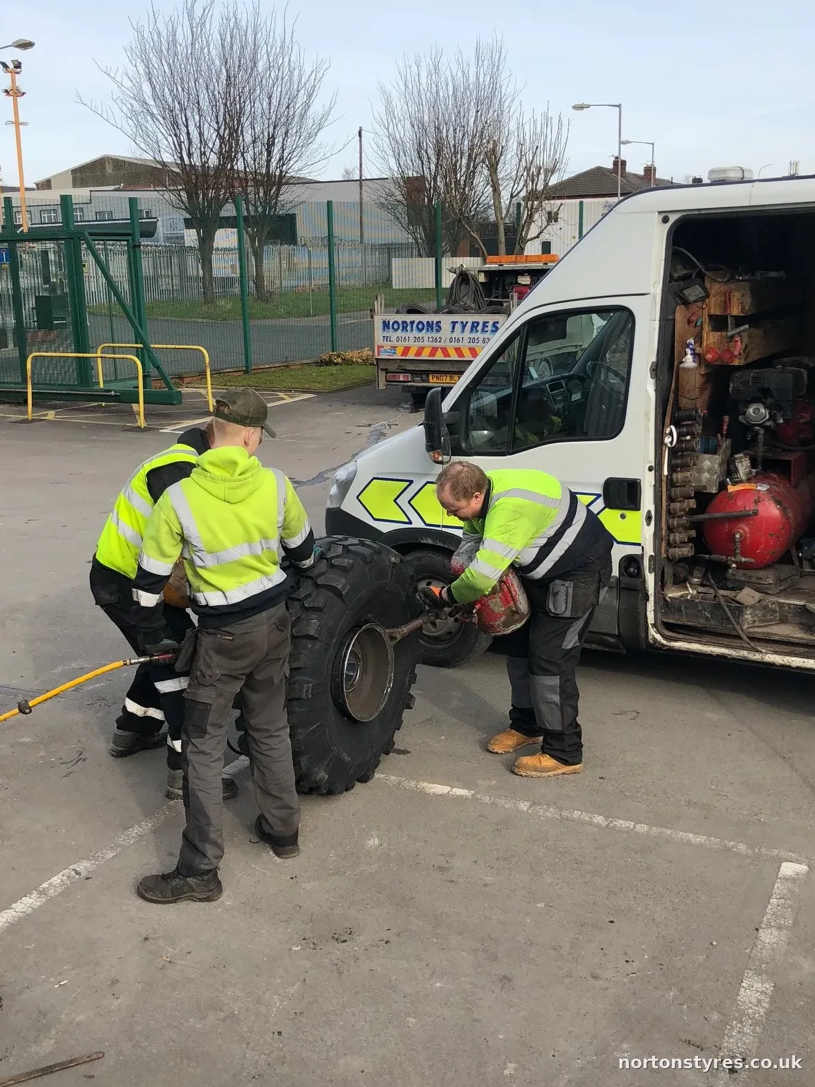Two fitters changing a tyre beside the open Nortons van, close view Two fitters changing a tyre beside the open Nortons van, close view