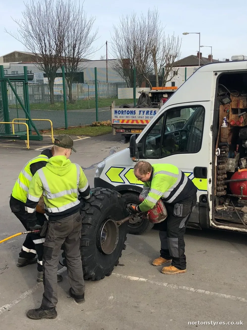 Two fitters changing a tyre beside the open Nortons van, detail Two fitters changing a tyre beside the open Nortons van, detail