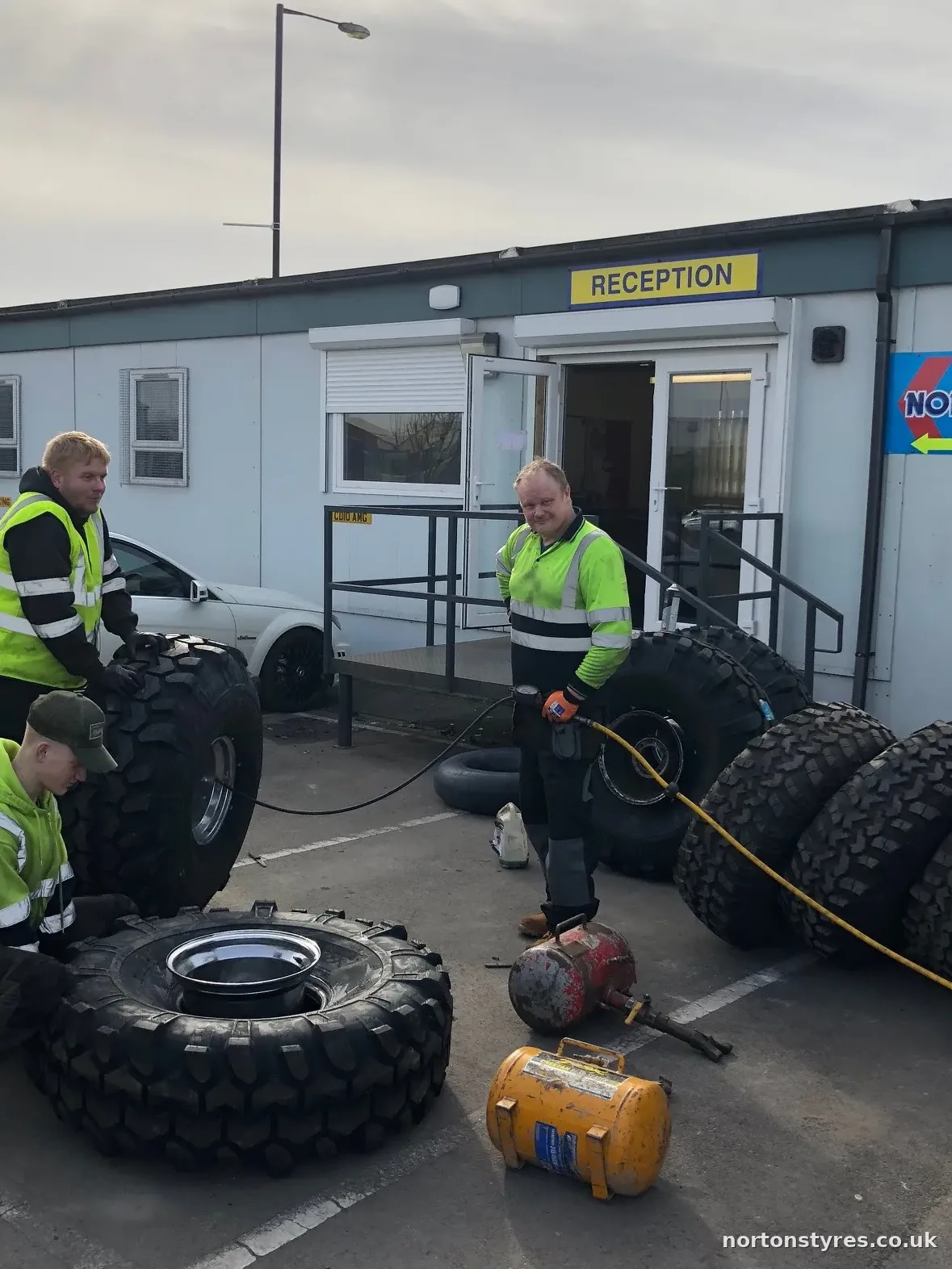 Fitters with tyres outside a site office on a call-out, close view Fitters with tyres outside a site office on a call-out, close view