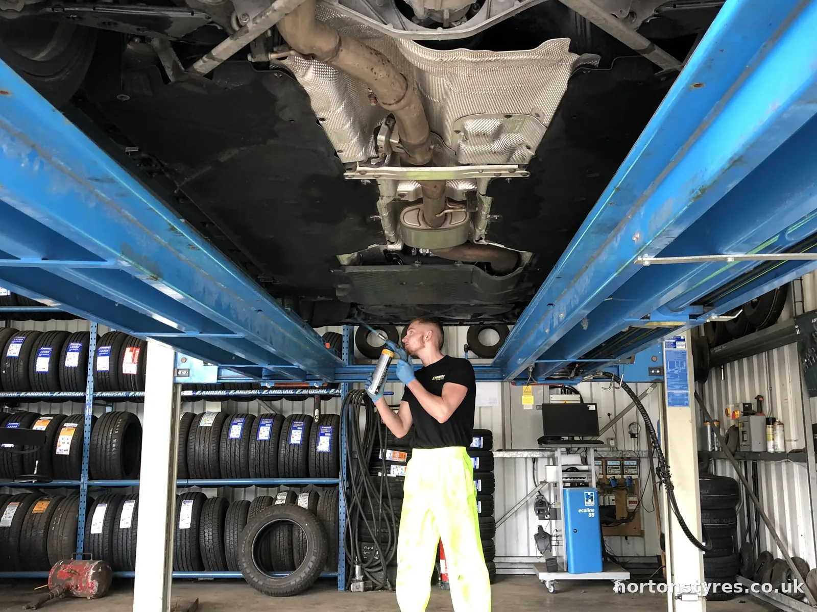 Fitter working under a car raised on the ramp, close view Fitter working under a car raised on the ramp, close view