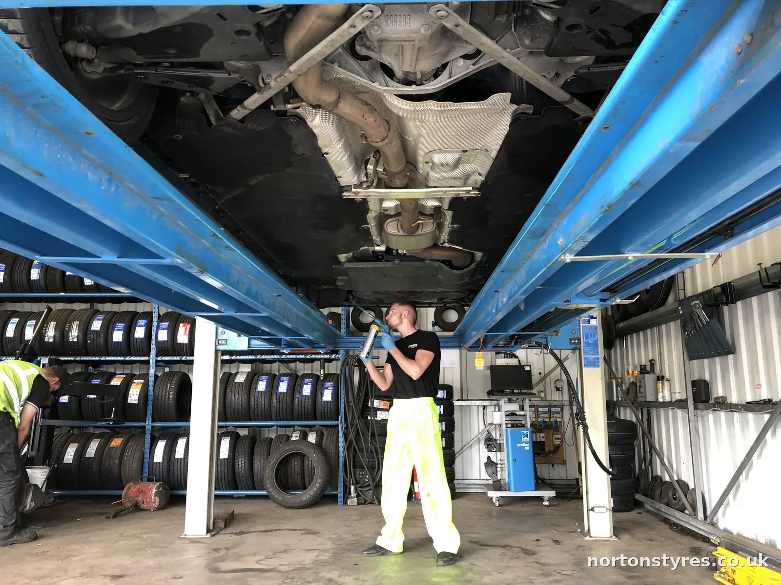 Fitter working under a car raised on the ramp Fitter working under a car raised on the ramp