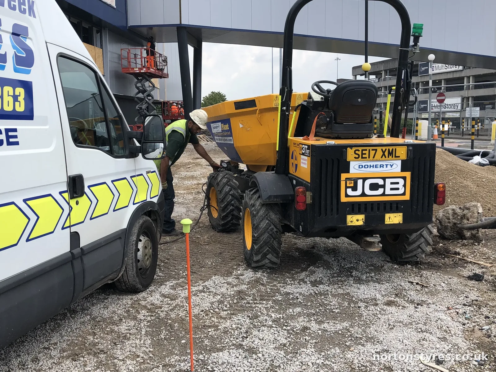 Fitter checking the tyre pressure on a JCB dumper, close view Fitter checking the tyre pressure on a JCB dumper, close view
