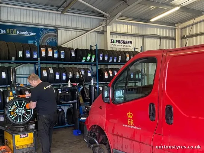 Fitter repairing a puncture on a red van in the tyre bay, detail Fitter repairing a puncture on a red van in the tyre bay, detail