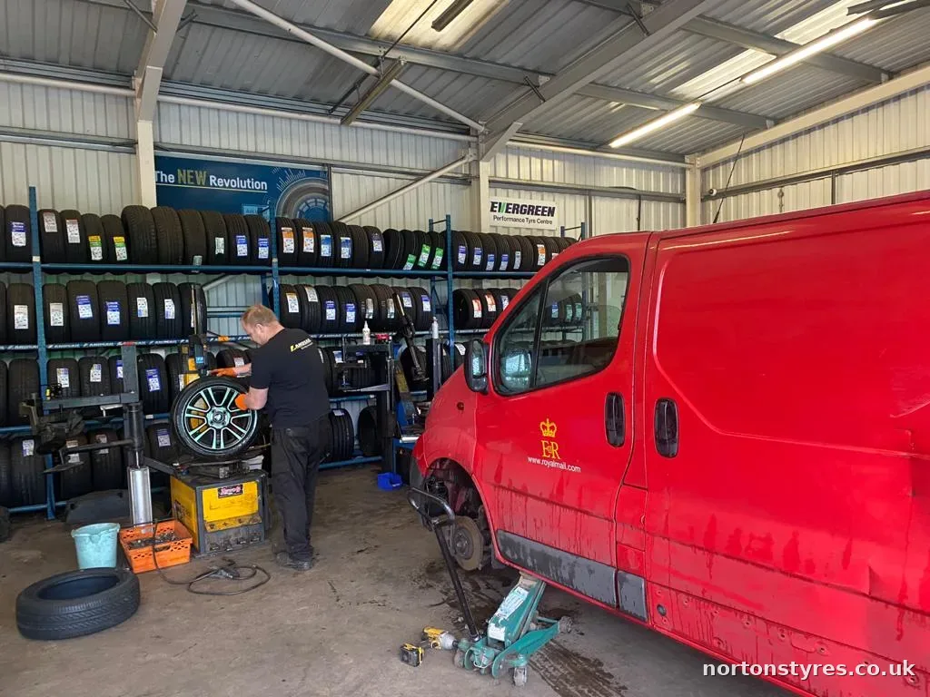 Fitter repairing a puncture on a red van in the tyre bay Fitter repairing a puncture on a red van in the tyre bay