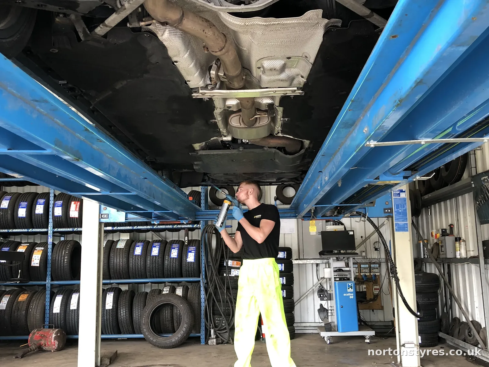 Fitter under a car on the alignment ramp, close view Fitter under a car on the alignment ramp, close view