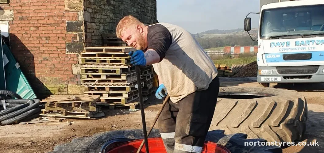 Fitter working on a tractor tyre on a farm, detail Fitter working on a tractor tyre on a farm, detail