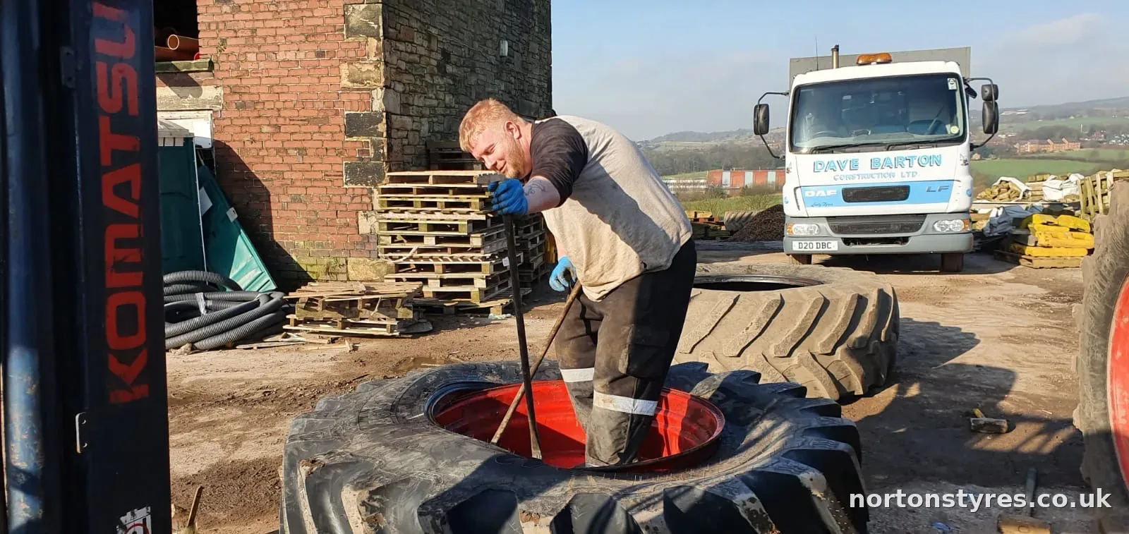 Fitter working on a tractor tyre on a farm Fitter working on a tractor tyre on a farm