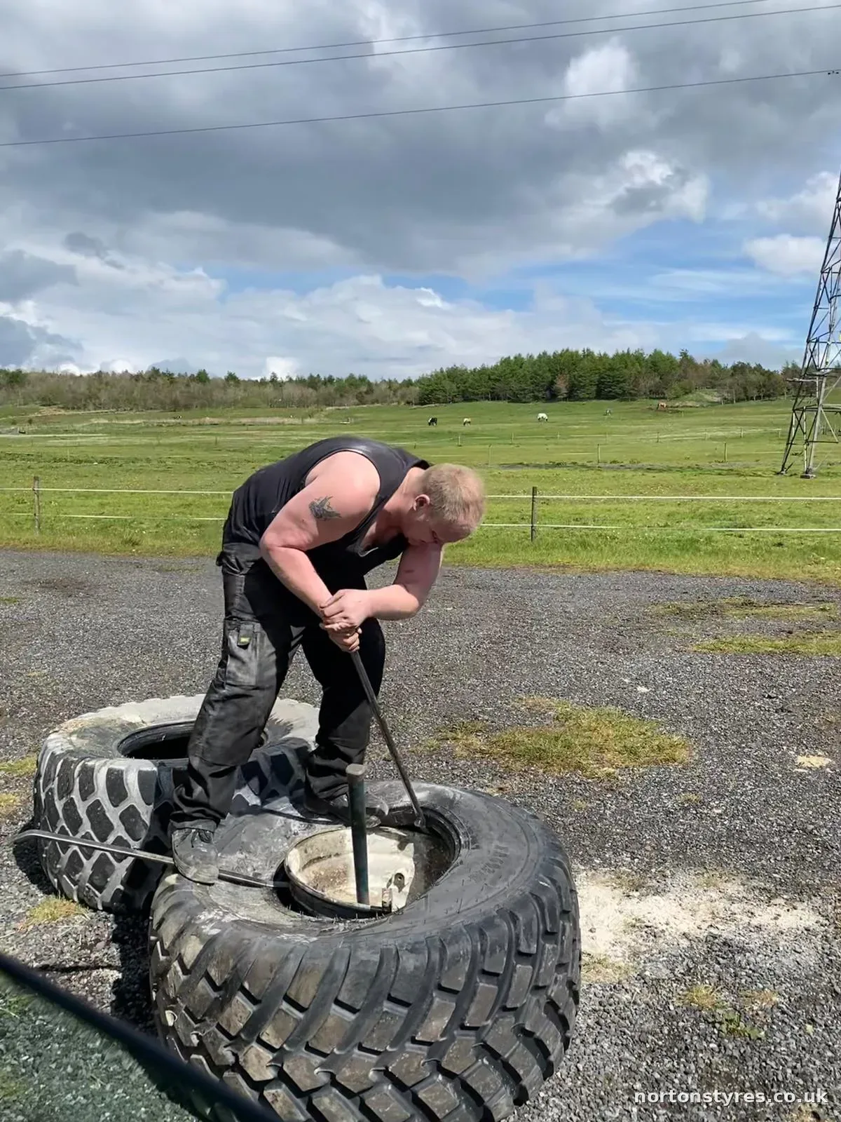Fitter working on a large trailer tyre in a field Fitter working on a large trailer tyre in a field