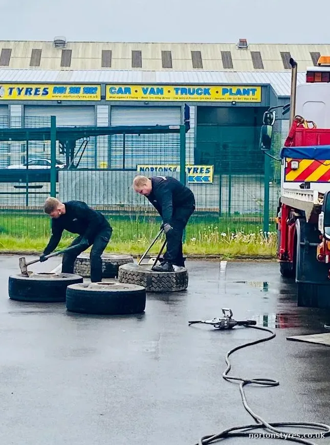 Two fitters changing truck tyres outside the bay, close view Two fitters changing truck tyres outside the bay, close view