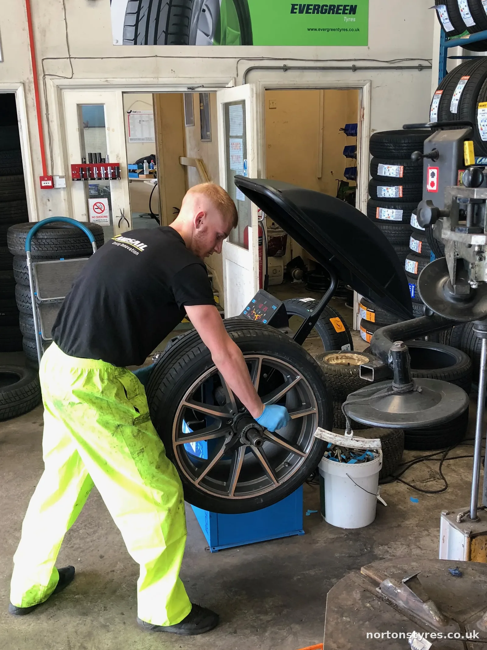 Fitter fitting a car wheel on the balancing machine, close view Fitter fitting a car wheel on the balancing machine, close view