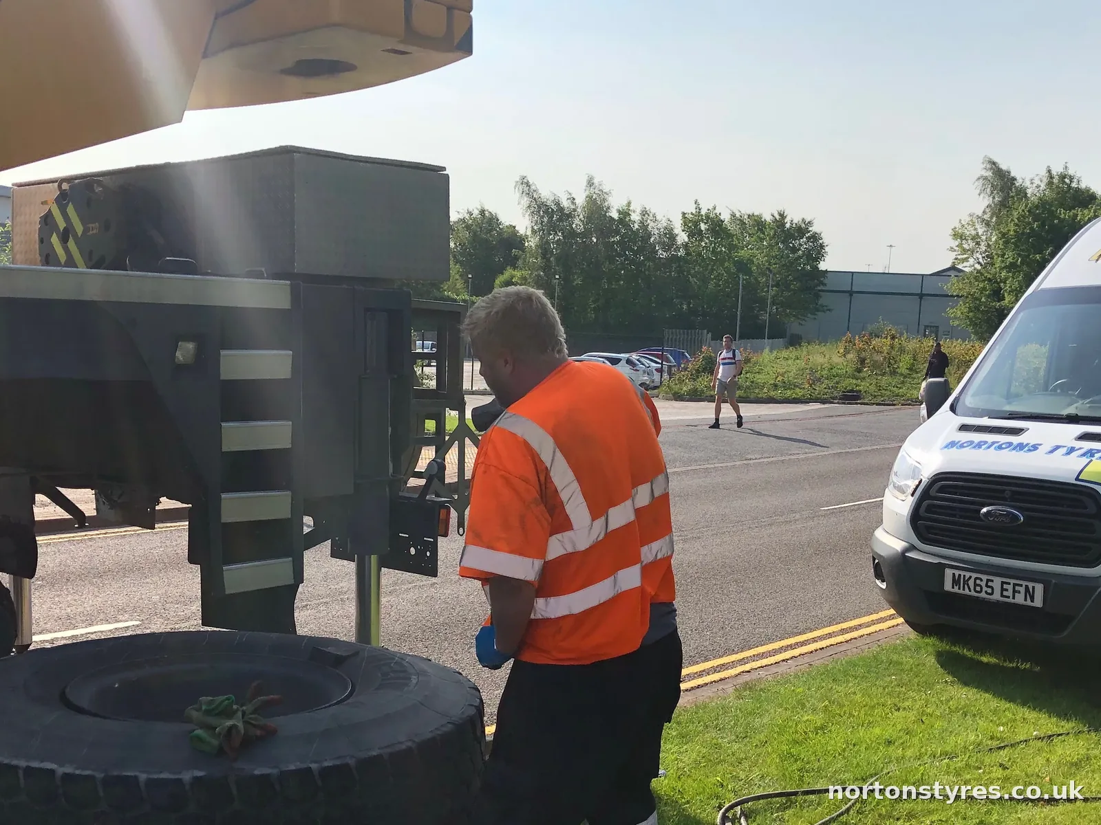 Fitter changing a lorry tyre with the Nortons van behind, detail Fitter changing a lorry tyre with the Nortons van behind, detail