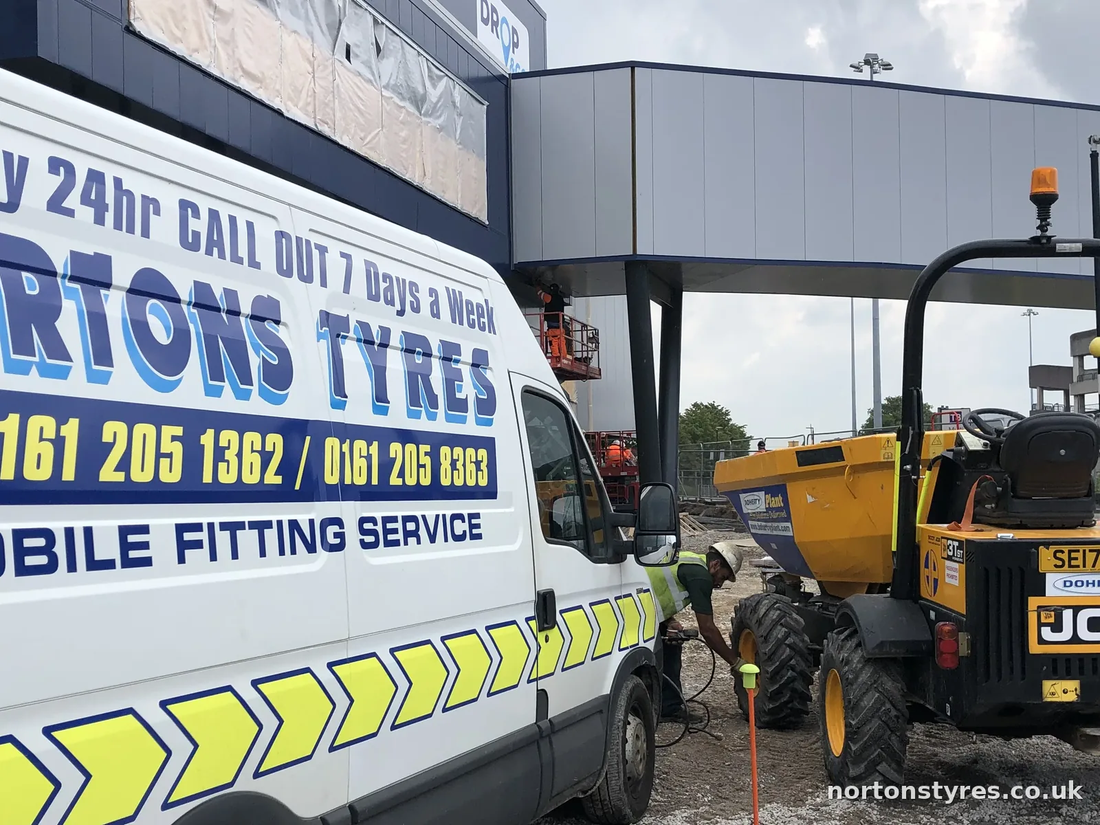 Nortons Tyres van beside a JCB dumper on a building site, detail Nortons Tyres van beside a JCB dumper on a building site, detail