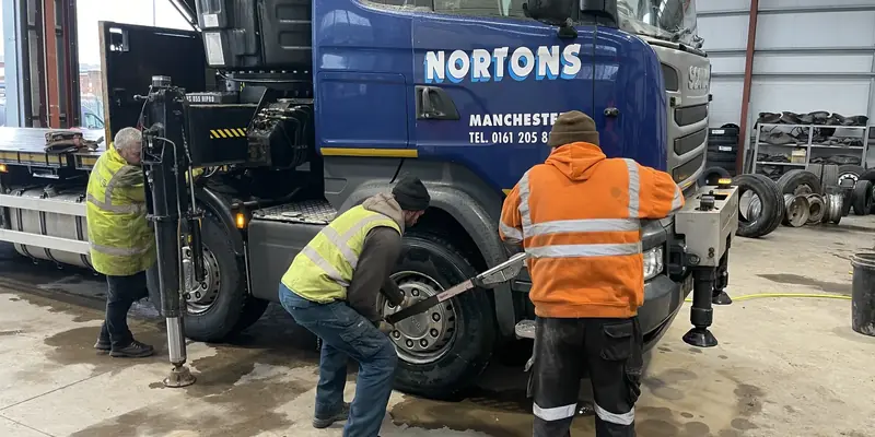 Fitters removing a front wheel from a Nortons lorry Fitters removing a front wheel from a Nortons lorry