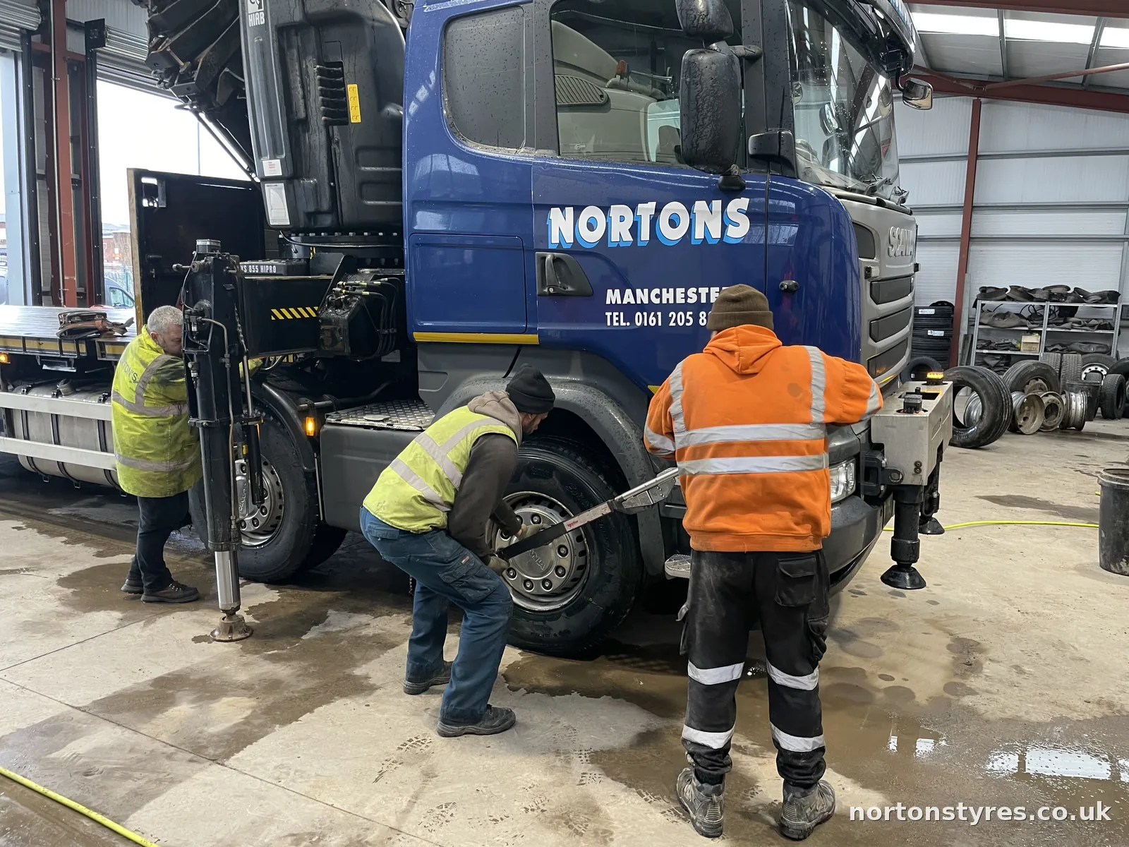Fitters removing a front wheel from a Nortons lorry Fitters removing a front wheel from a Nortons lorry