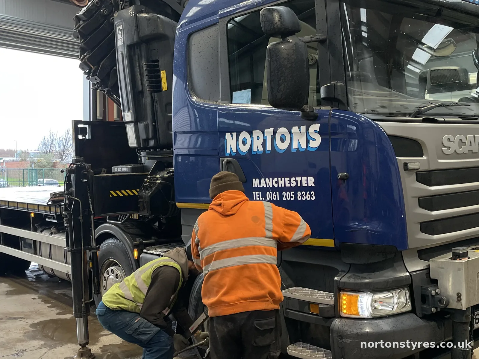 Fitters changing a Nortons lorry tyre in the workshop, detail Fitters changing a Nortons lorry tyre in the workshop, detail