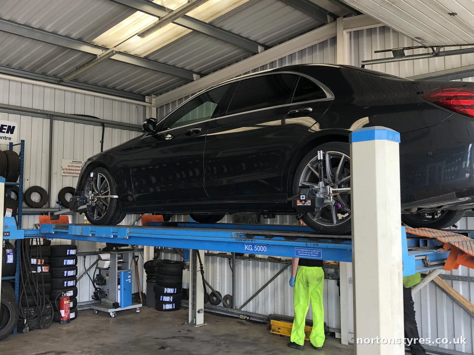 Fitter checking wheel alignment on a raised car, close view Fitter checking wheel alignment on a raised car, close view