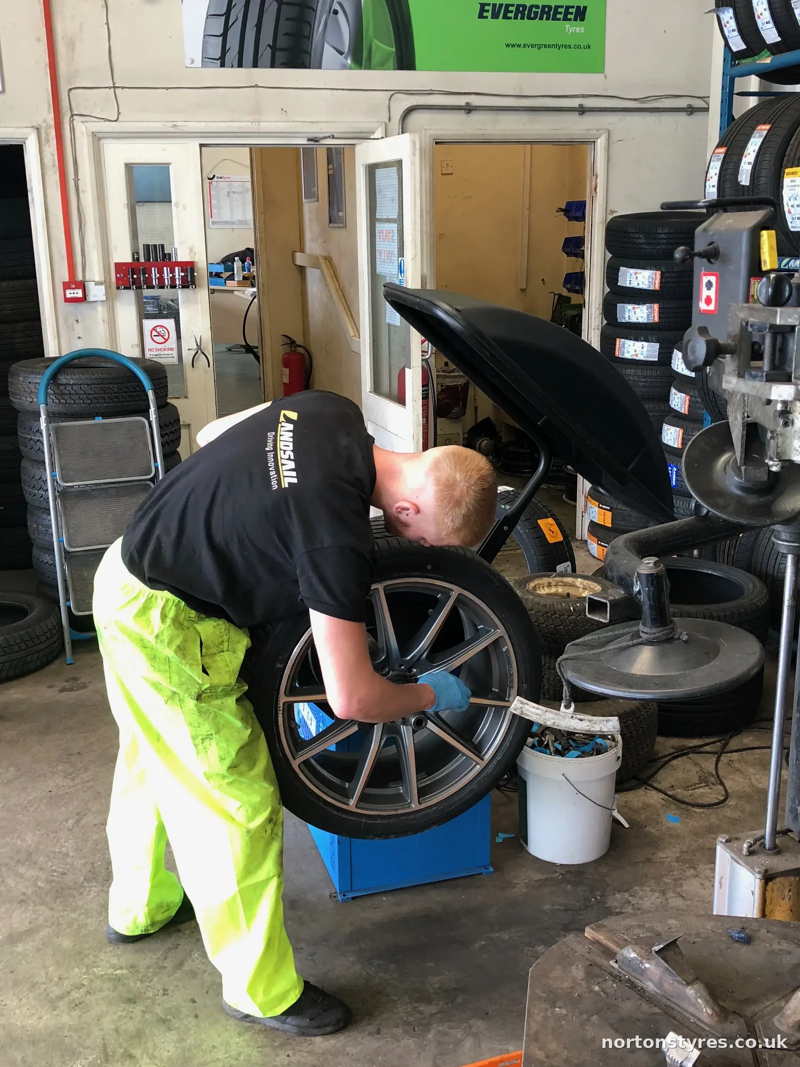 Fitter fitting a car wheel to the balancing machine, close view Fitter fitting a car wheel to the balancing machine, close view