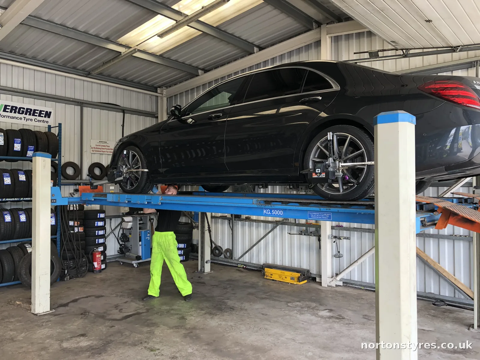 Car on the ramp in the alignment bay with the fitter underneath Car on the ramp in the alignment bay with the fitter underneath